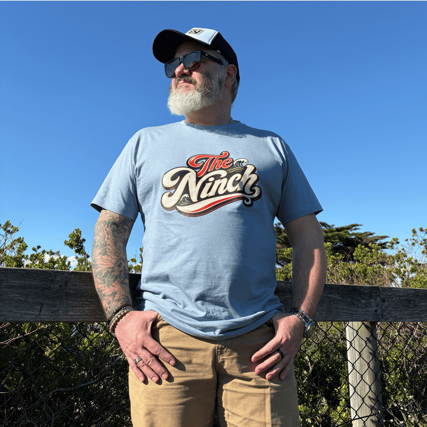 Man wearing The Ninch dusty blue tee with vintage front graphic overlooking the Mornington Peninsula coast