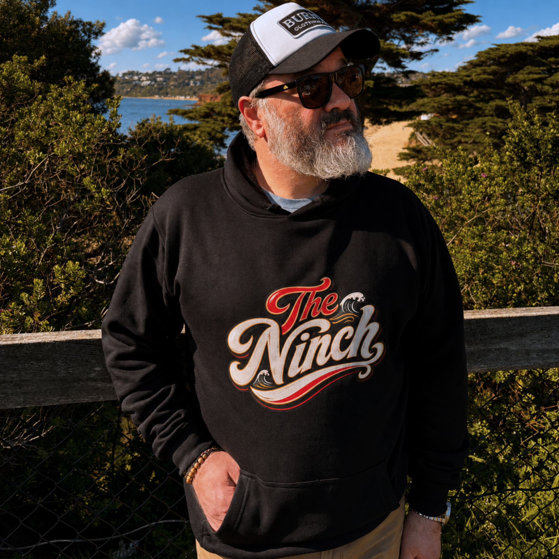 Man wearing The Ninch black hoodie with vintage front graphic on the Mornington Peninsula coastline