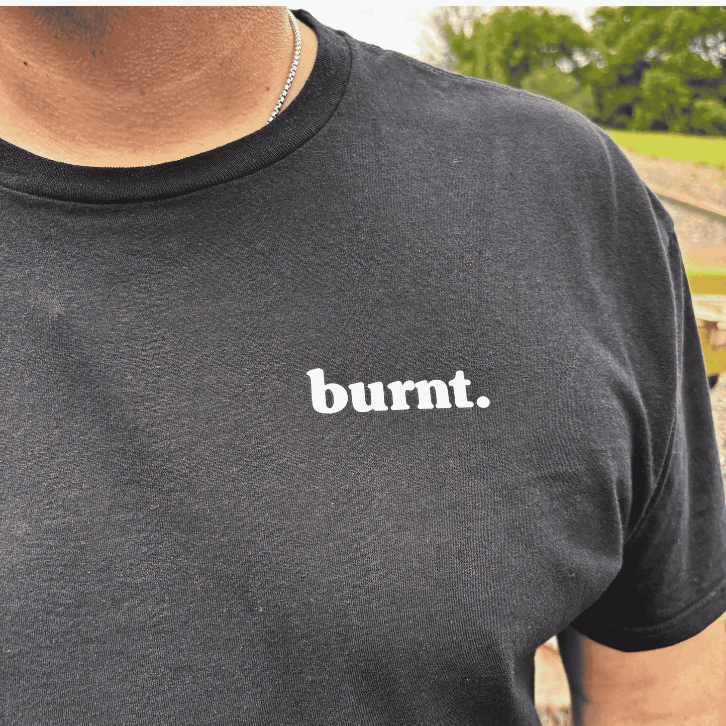 Close-up detail of Burnt black t-shirt featuring white burnt. chest logo