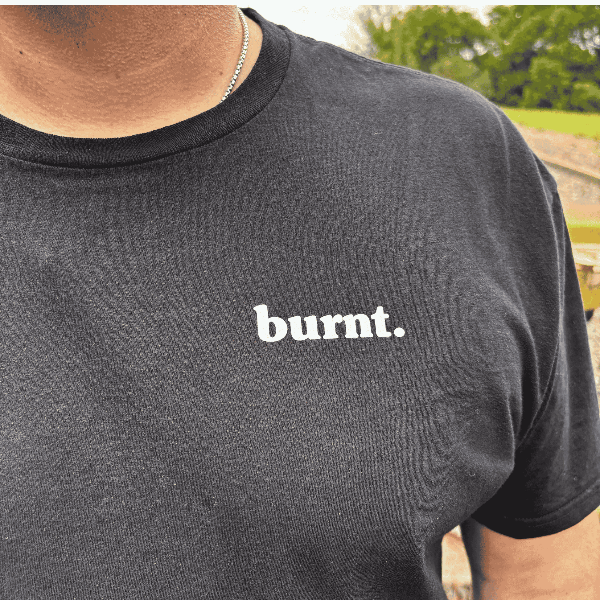 Close-up detail of Burnt black t-shirt featuring white burnt. chest logo