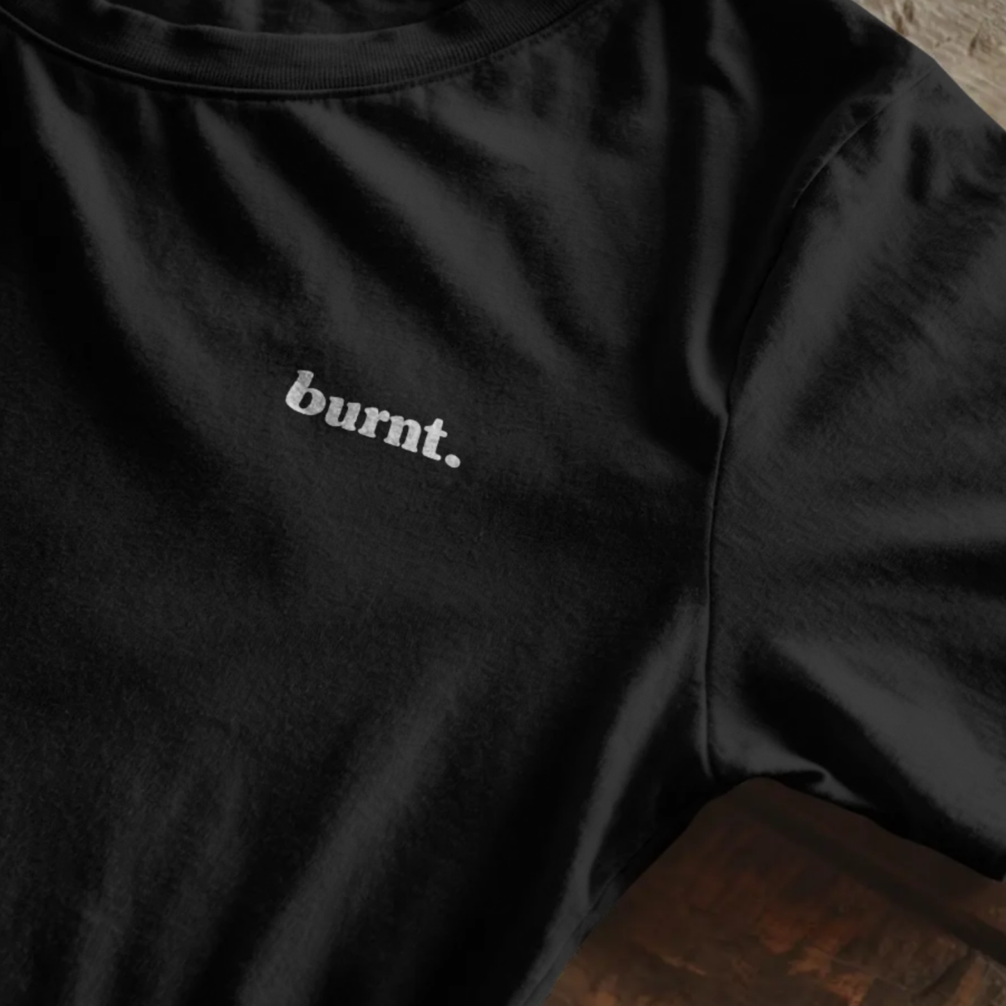 Close-up flatlay of Burnt black t-shirt featuring white burnt. chest logo