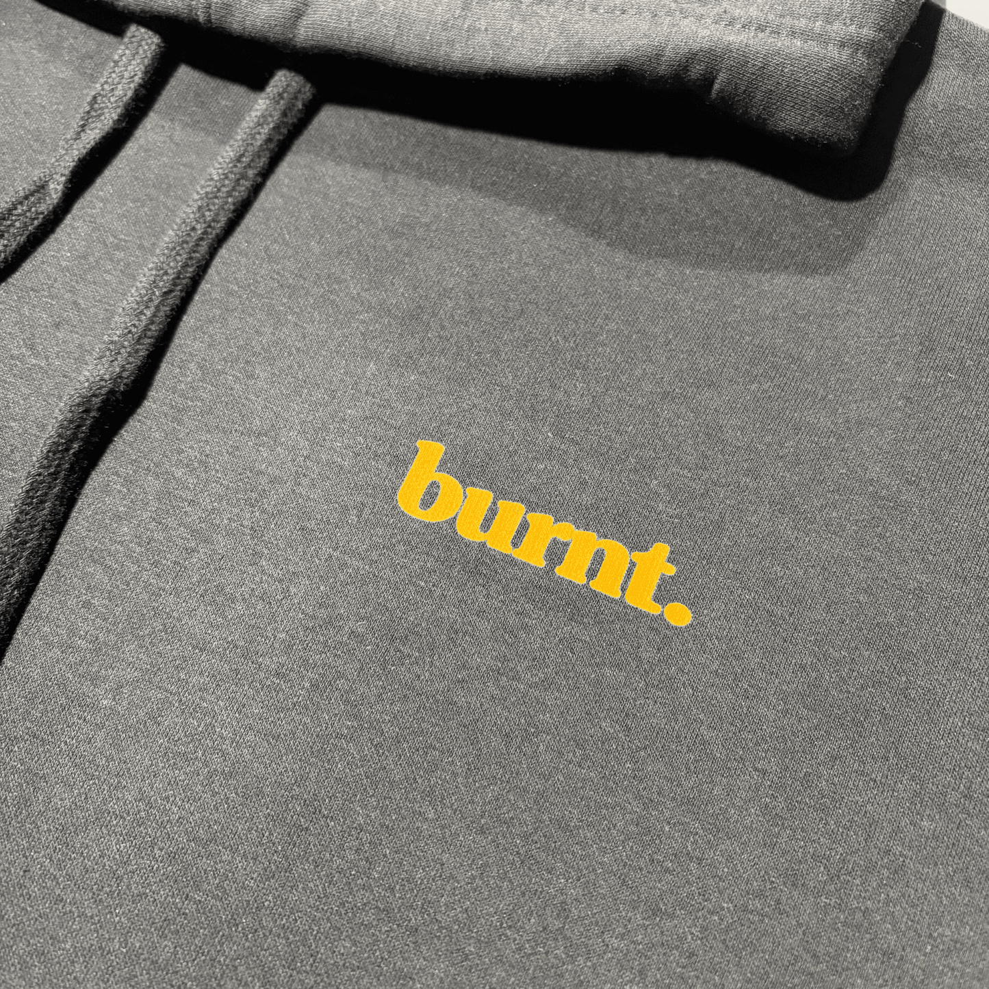Close-up of the small burnt. logo printed inside the black hoodie