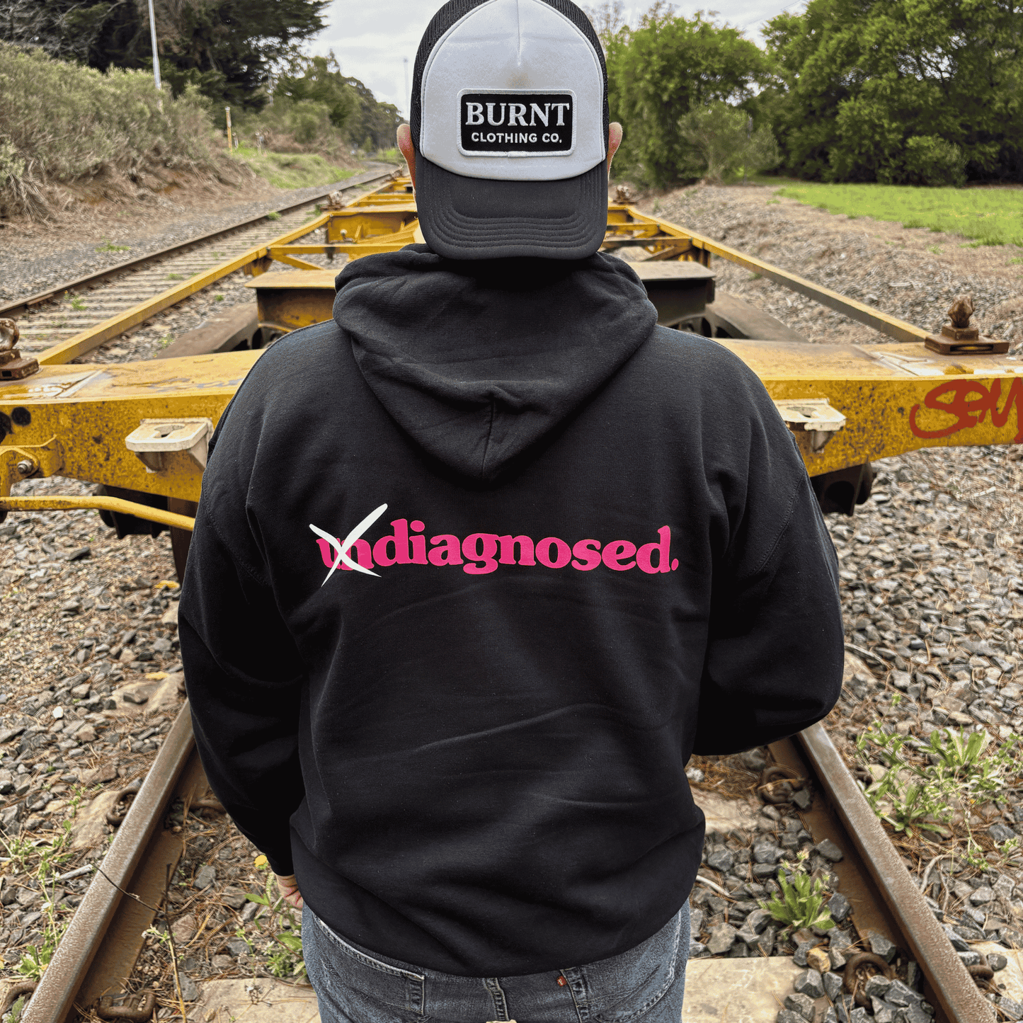 Back view of diagnosed. black hoodie with pink print by Burnt Clothing Co