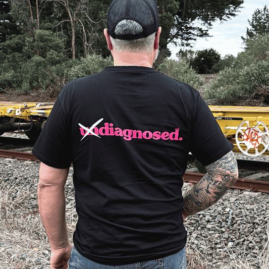 Man wearing the diagnosed. black T-shirt with pink and white back graphic
