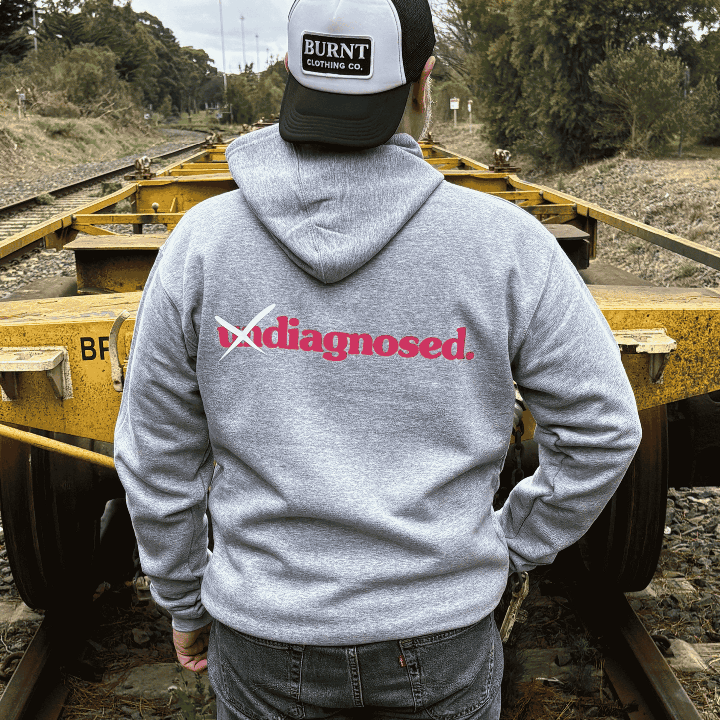 Back view of diagnosed. grey hoodie with pink print by Burnt Clothing Co