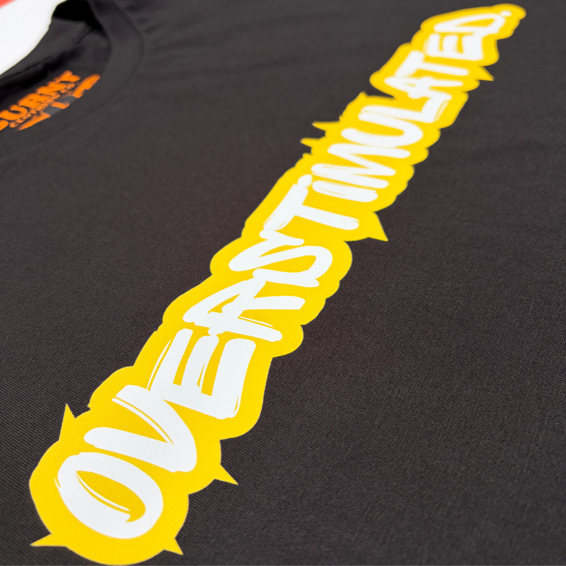 Close-up of the yellow and white overstimulated. print on a black tee