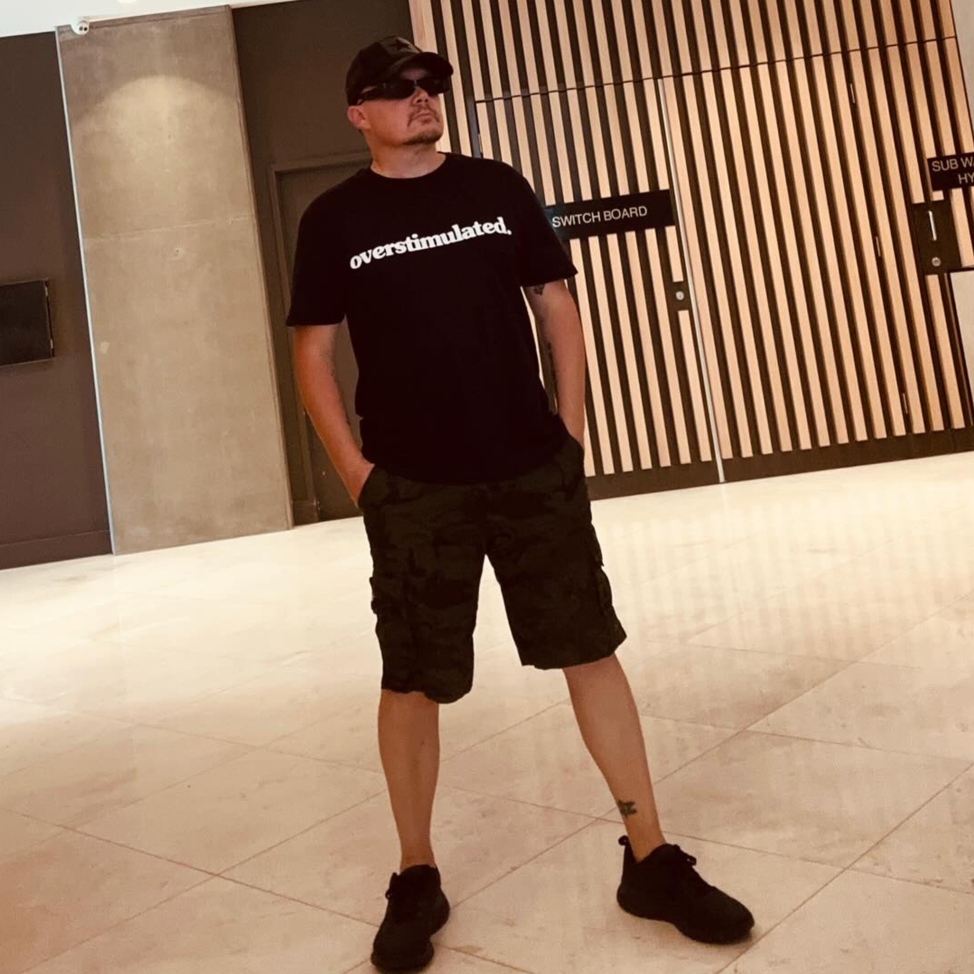 Full-body view of a black overstimulated. tee
