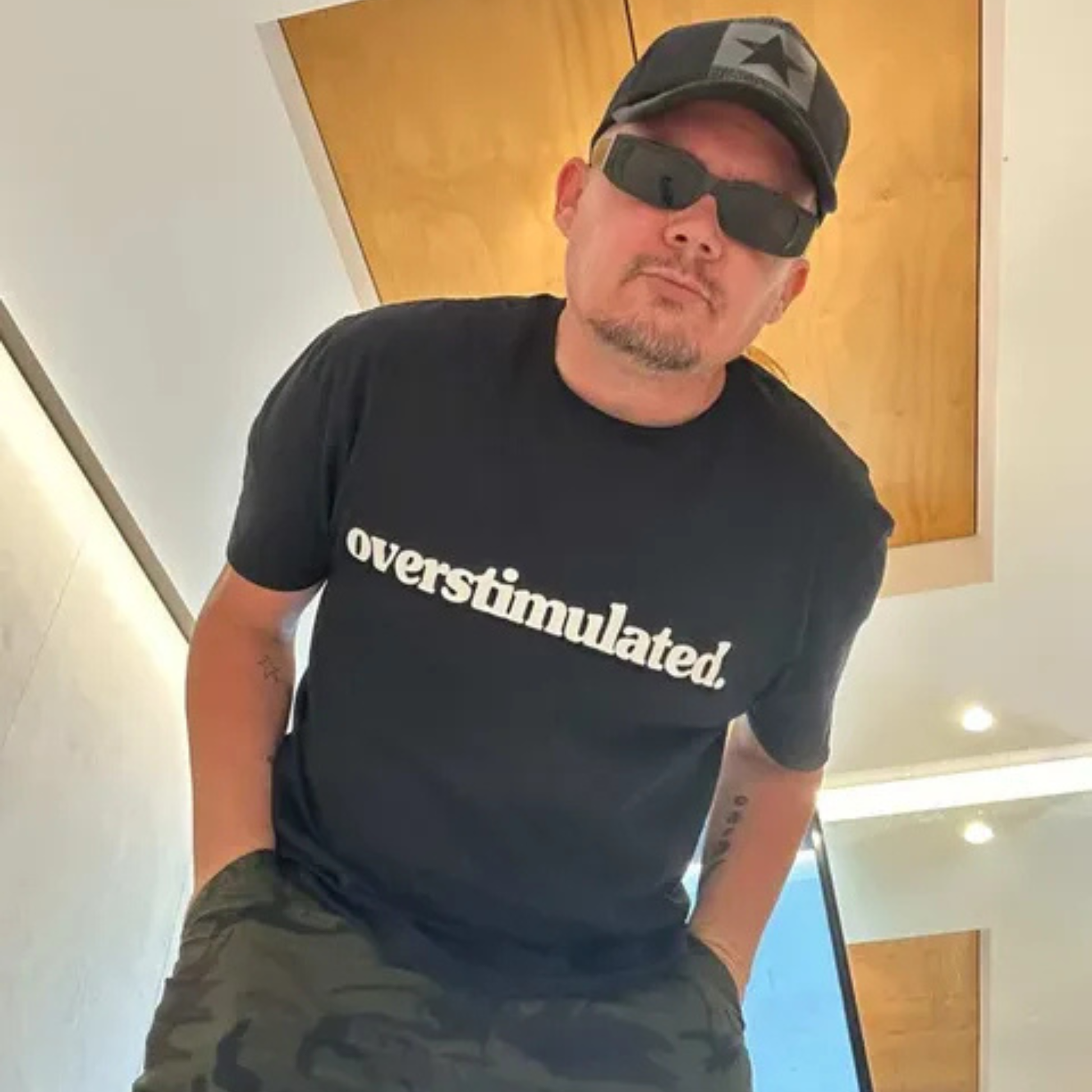 Man wearing a black overstimulated. tee with white print