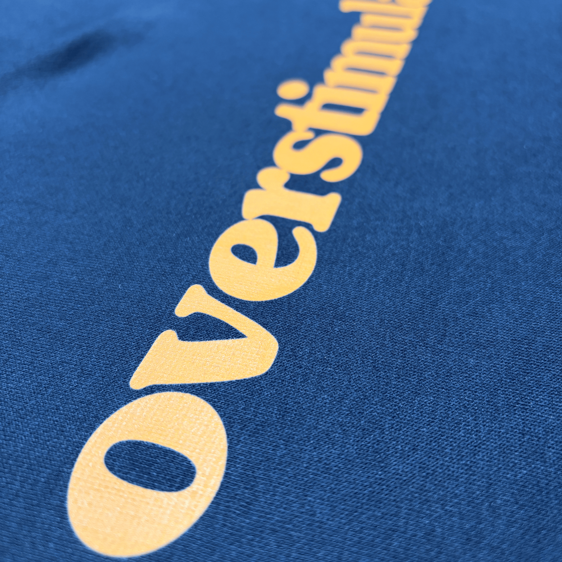 Close-up of the burnt orange overstimulated. print on a black cotton T-shirt.