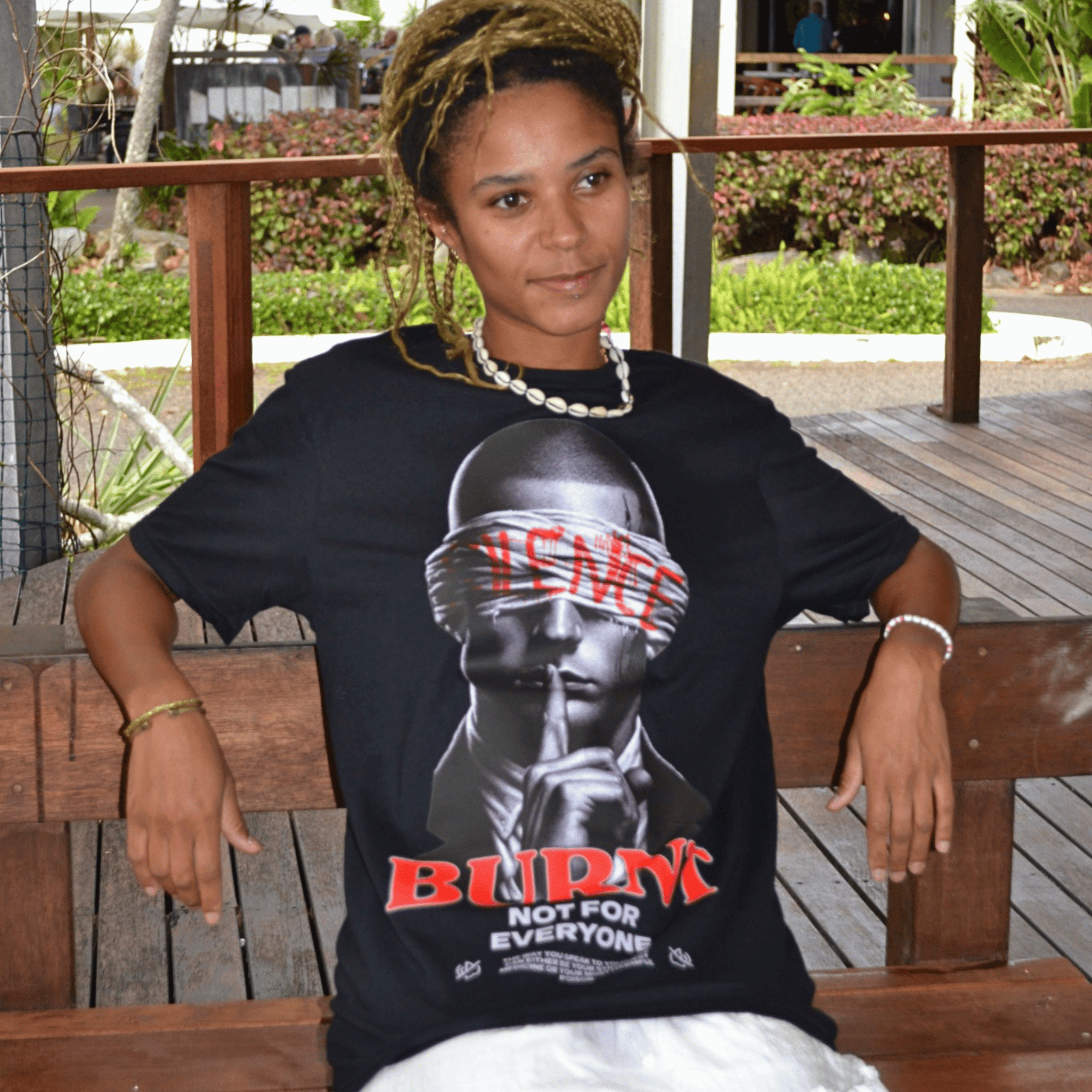 Seated model wearing The Quiet War black graphic tee