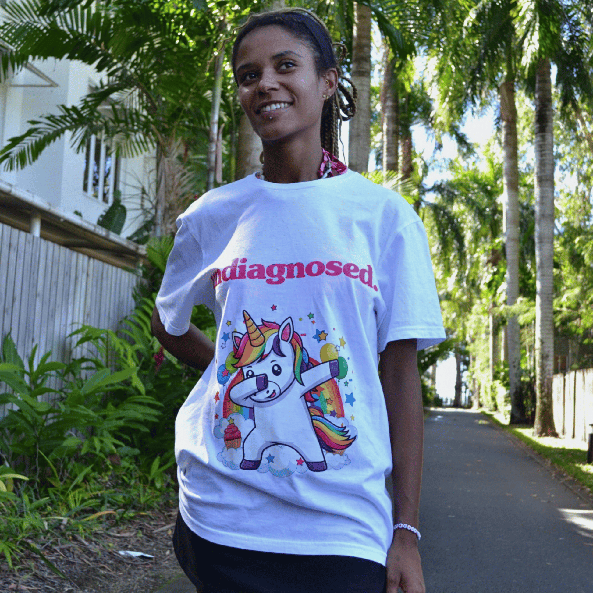 Front print undiagnosed. Unicorn white tee worn outdoors